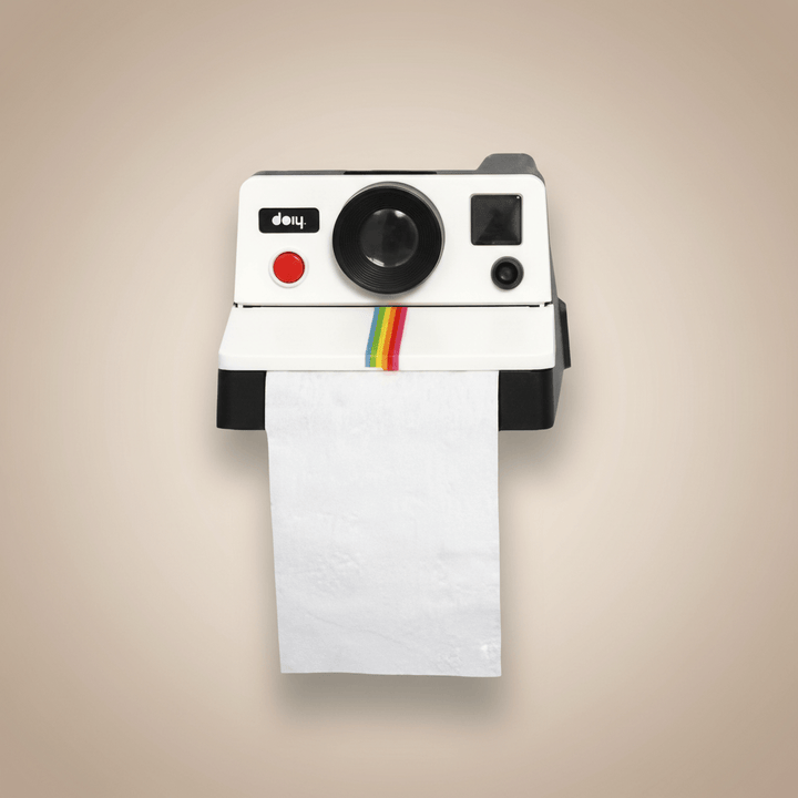 Polaroid camera-shaped toilet paper holder on a beige wall