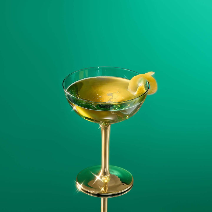 Cocktail in a glass with a lemon twist on a green background