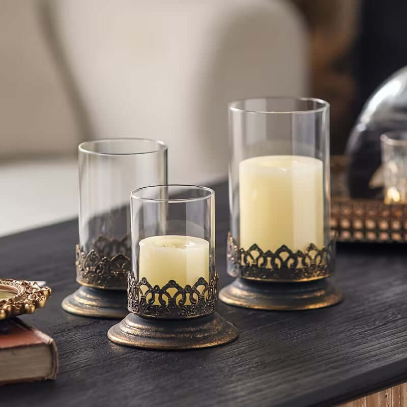 Three glass candle holders with candles on a wooden surface