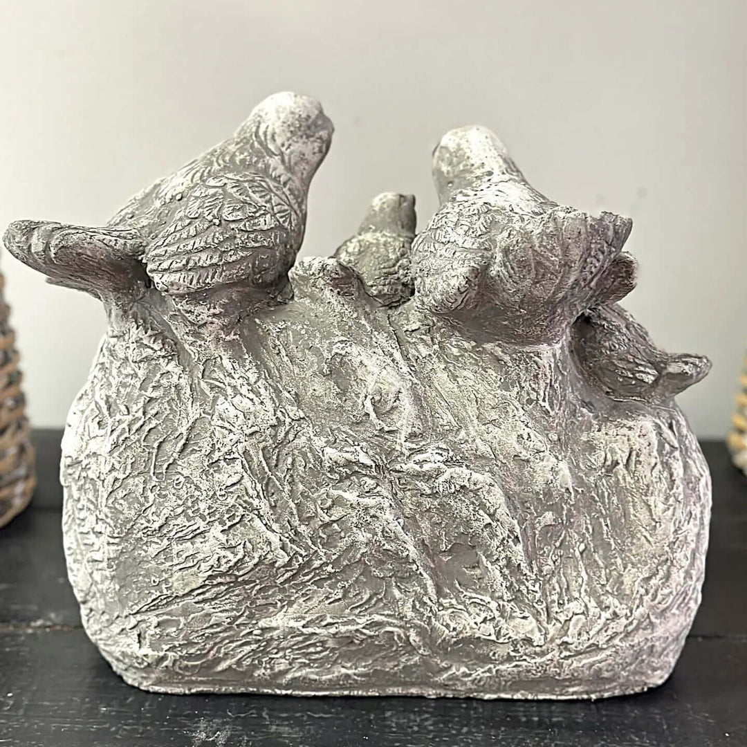 Vintage cement birds welcome sign with four detailed songbirds and "WELCOME" carved into a rugged stone base for garden decor.