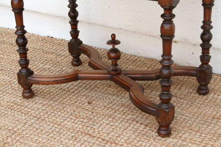 Intricate woodwork detail of 19th Century French Walnut Antique Writing Table legs and base on woven mat.