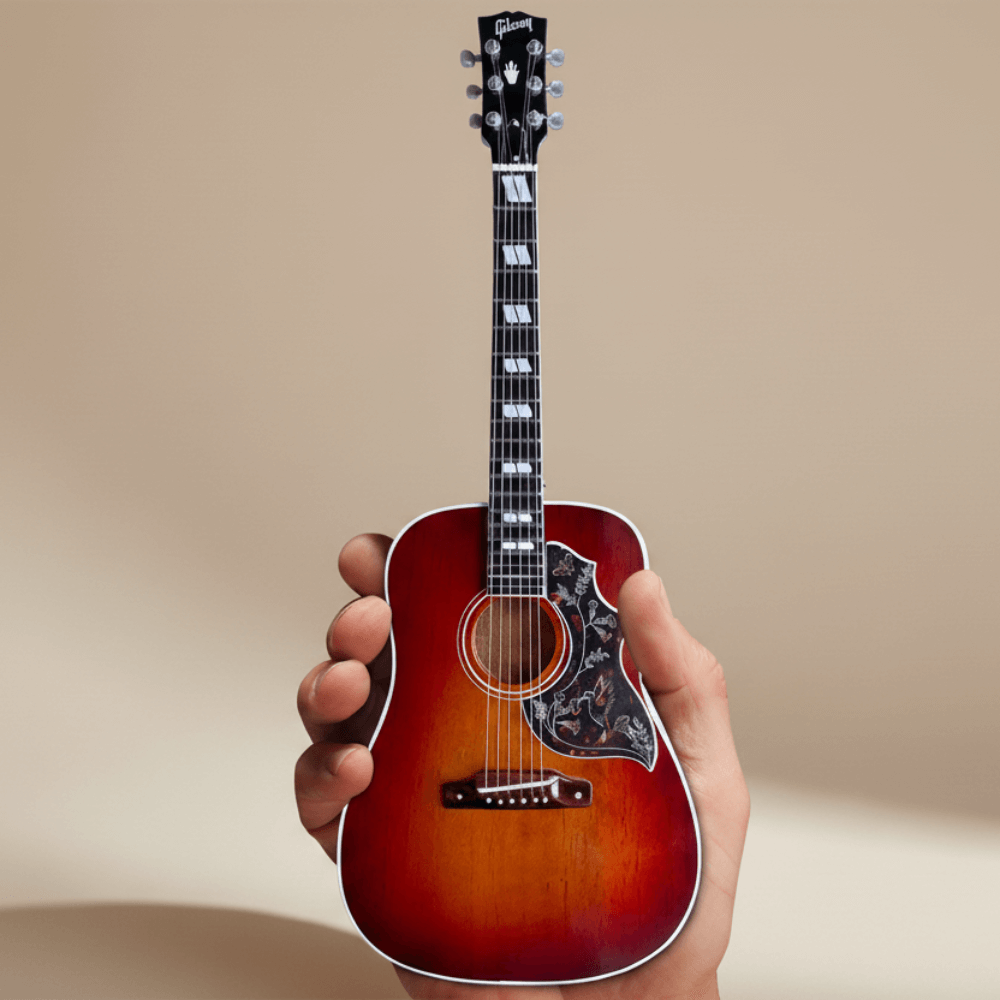 Gibson Hummingbird Vintage Cherry Mini Guitar Replica held in hand, showcasing detailed craftsmanship and iconic design elements.
