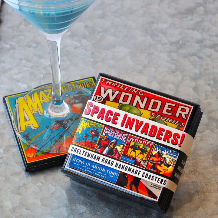 Box of 'Space Invaders' coasters with a blue cocktail on a textured surface