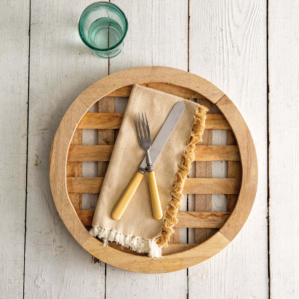 Farmhouse wood charger plate with slatted design on white table, featuring vintage flatware and napkin, ideal for rustic dining decor.