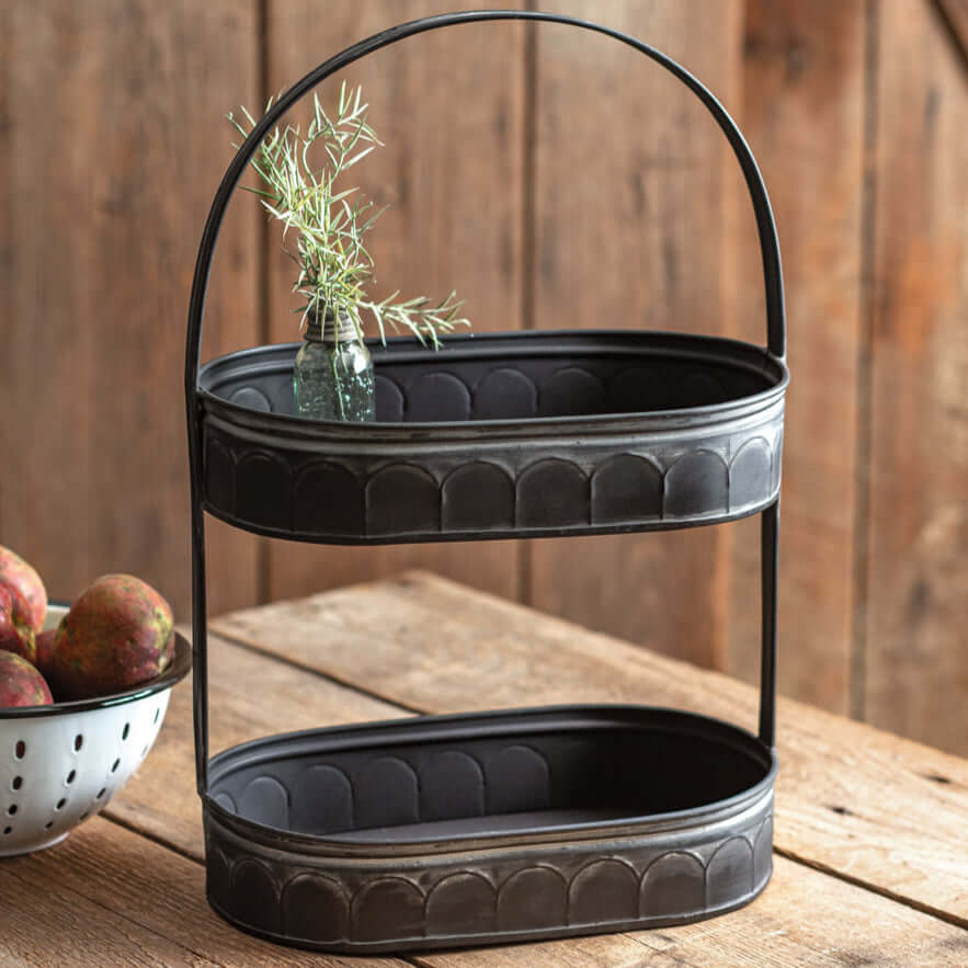 Vintage Farmhouse Black Galvanized Tiered Tray with arched handle on a rustic wooden table.