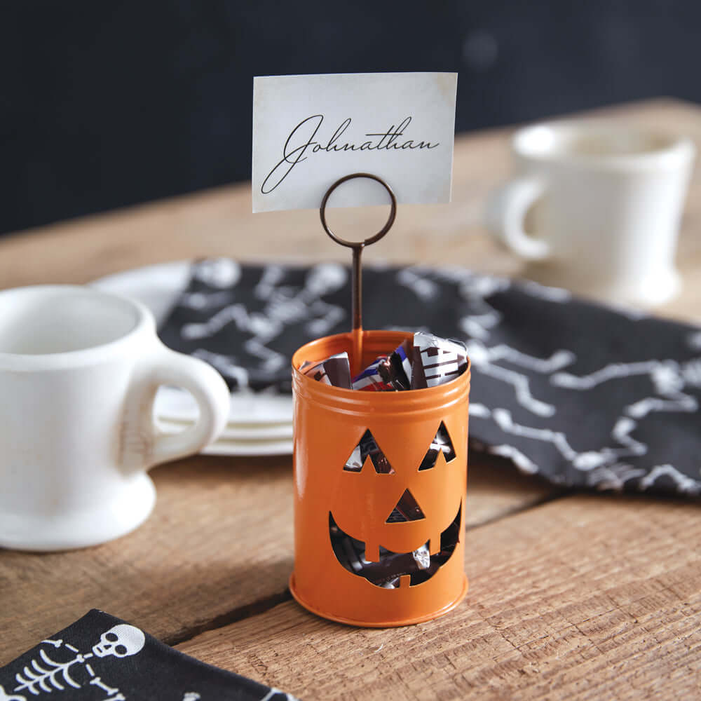 Halloween Jack-O-Lantern metal place card holder on wooden table with name card "Johnathan."