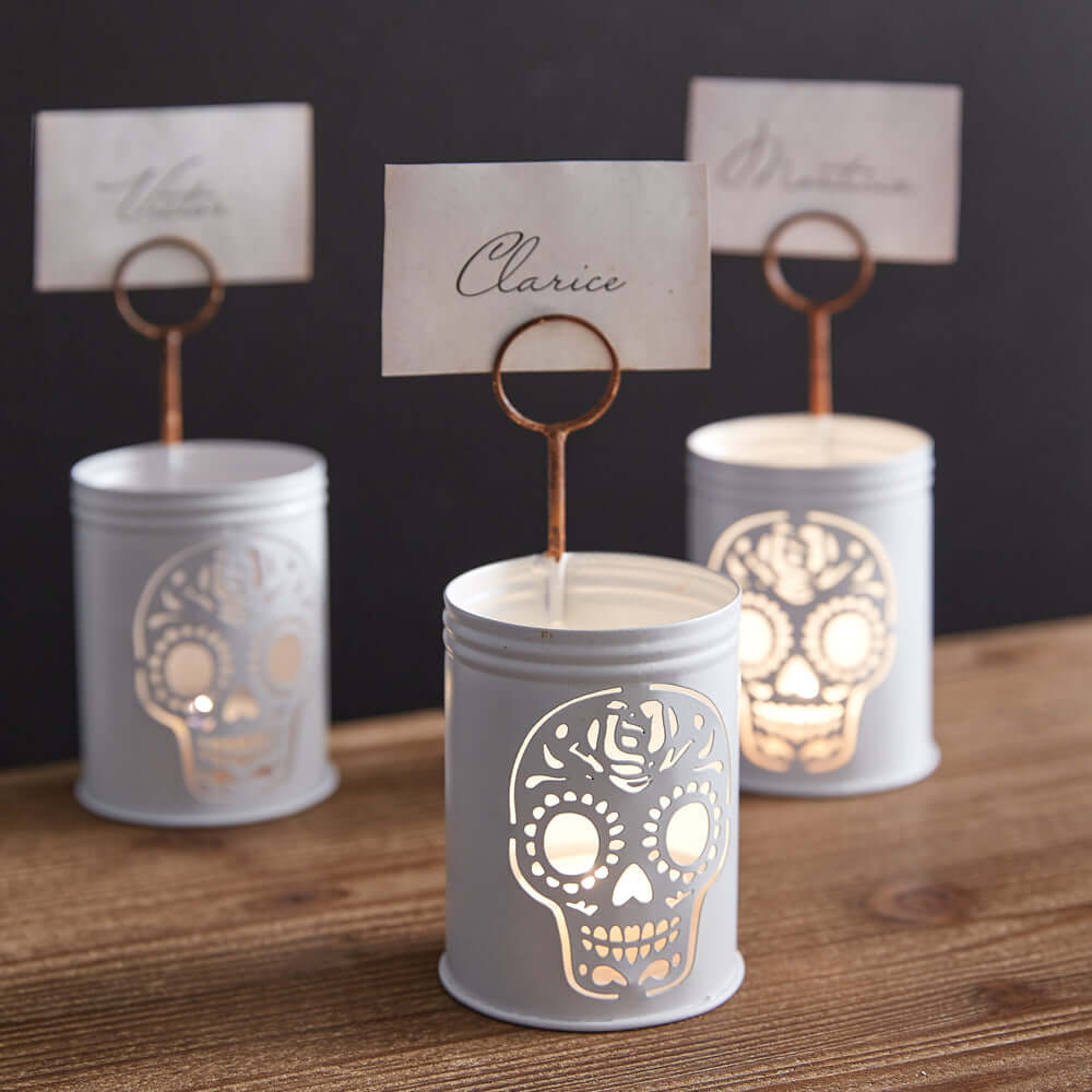 Vintage Sugar Skull Metal Place Card Holders with glowing candlelight, perfect for Dia de los Muertos and Halloween gatherings.