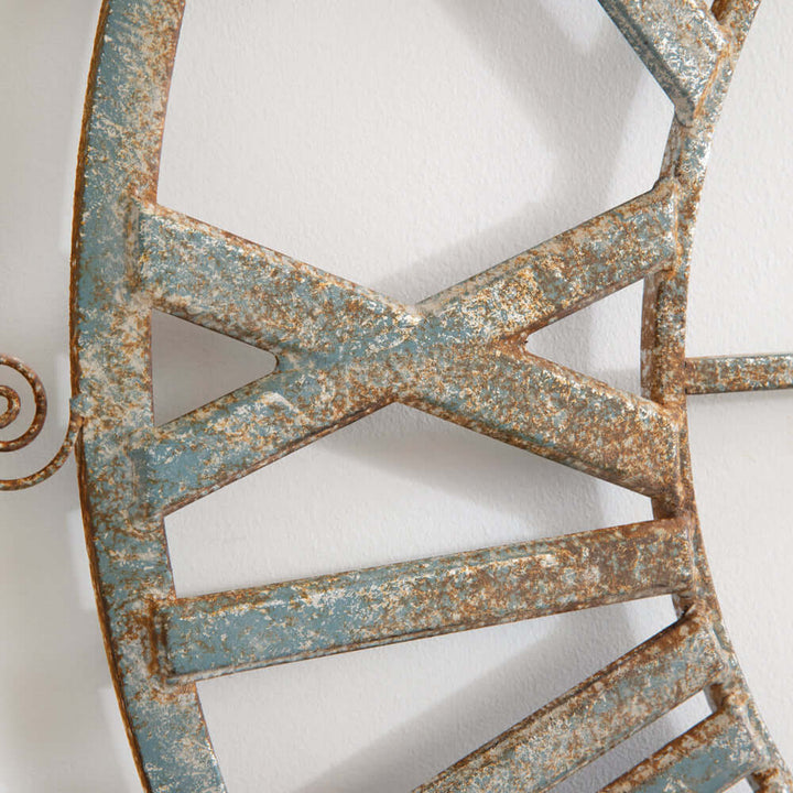 Close-up of distressed metal frame on large vintage farmhouse wall clock with Roman numerals, showcasing rustic weathered details.