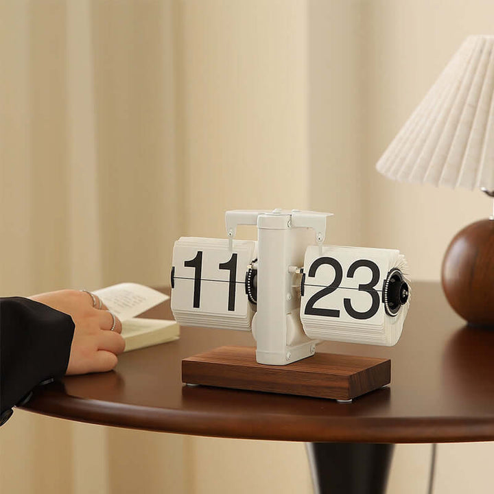 Tabletop flip clock with wooden base on a desk, blurred background