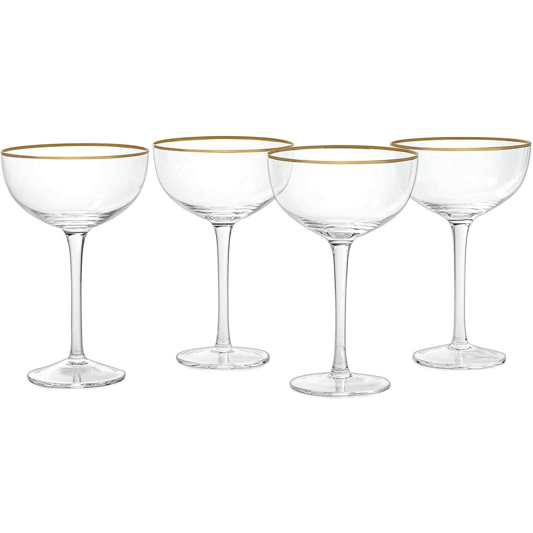 Four clear cocktail glasses with gold rims on a white background