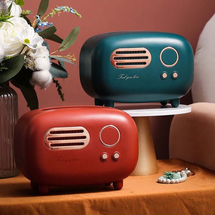 Two vintage-style radios, one red and one blue, on a wooden surface with flowers and a vase in the background.