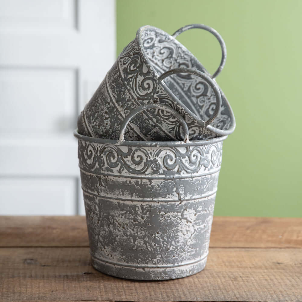 Set of 2 antique metal buckets with handles, featuring intricate filigree and distressed finish for vintage farmhouse decor.