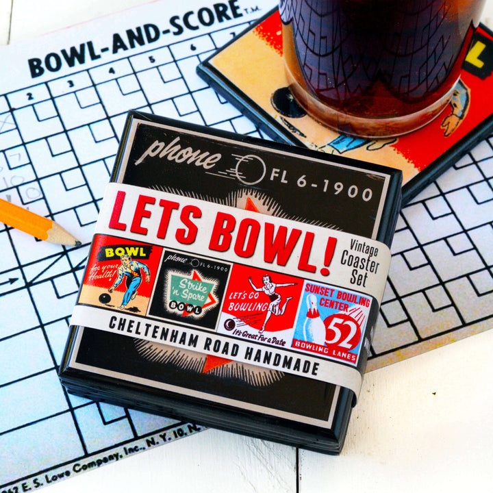 Vintage-style 'Let's Bowl!' coaster set packaging on a checkered tablecloth with a glass of beer.
