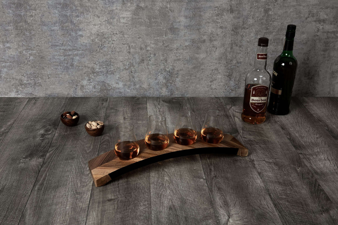 Wooden drink tray with four glasses and two bottles on a wooden surface.