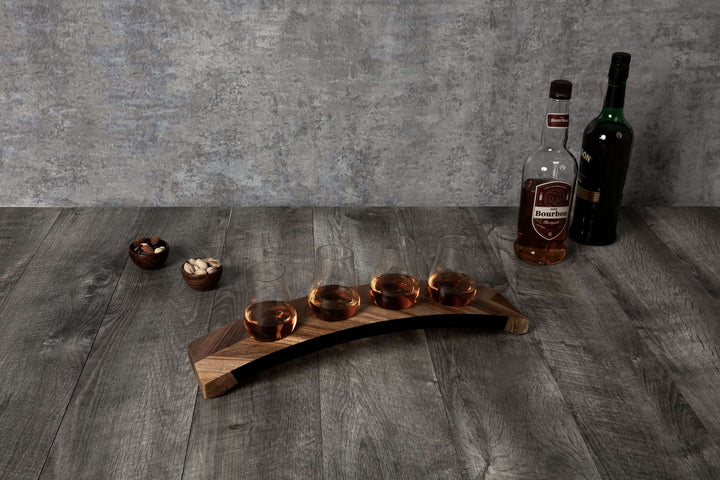 Wooden drink tray with four glasses and two bottles on a wooden surface.