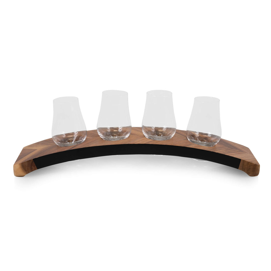 Four glass tasting cups on a curved wooden holder against a white background