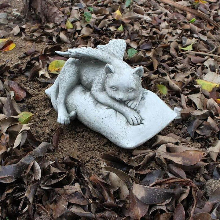 Angelic Cat Memorial Statue depicting a peaceful cat with angel wings resting on a cushion among fallen leaves.