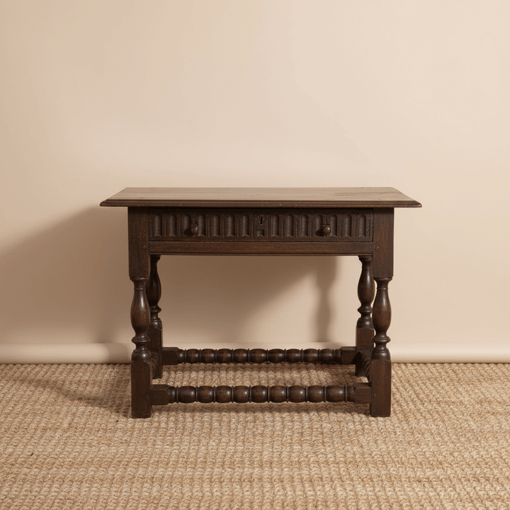 Wooden side table with a single drawer on a beige carpet against a beige wall