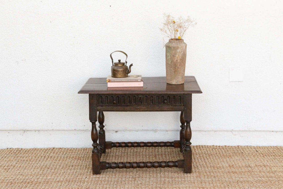 Wooden side table with decorative items against a white wall