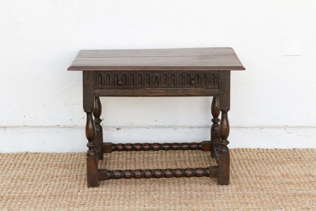 Wooden side table with intricate carvings on a white wall background