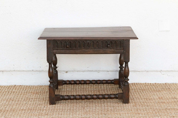 Wooden side table with intricate carvings on a white wall background