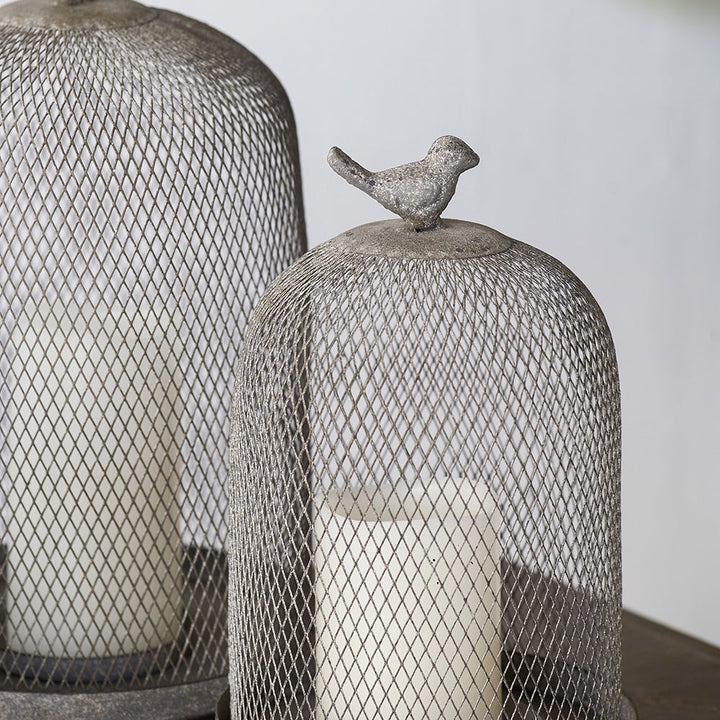 Decorative mesh domes with a bird figurine on top against a neutral background