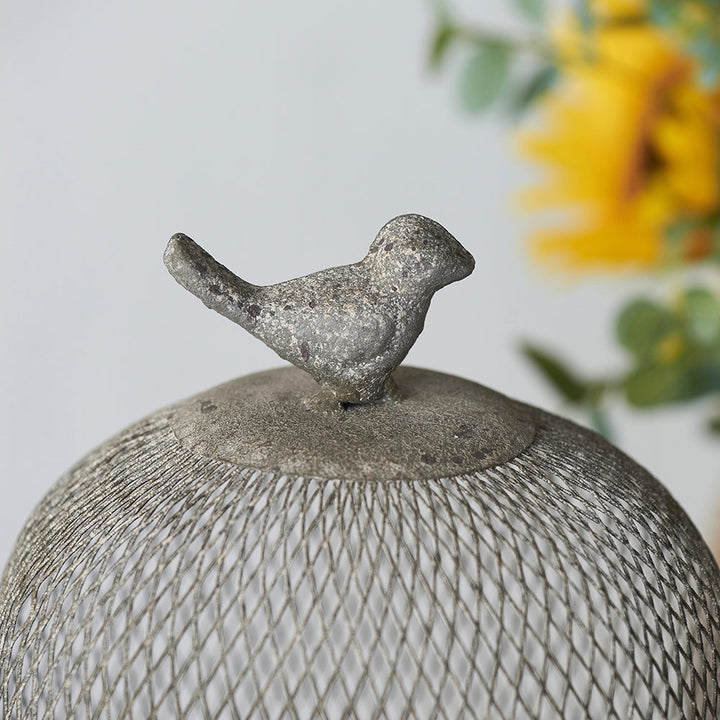 Decorative bird on top of a dome-shaped lantern with a blurred floral background