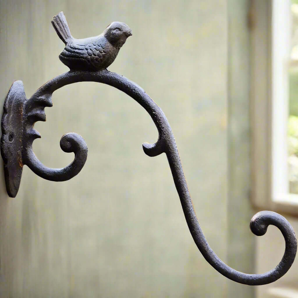 Antique cast iron bird wall hook with elegant curves and a perched songbird for vintage home decor.