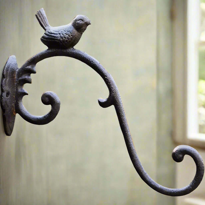 Antique cast iron bird wall hook with elegant curves and a perched songbird for vintage home decor.