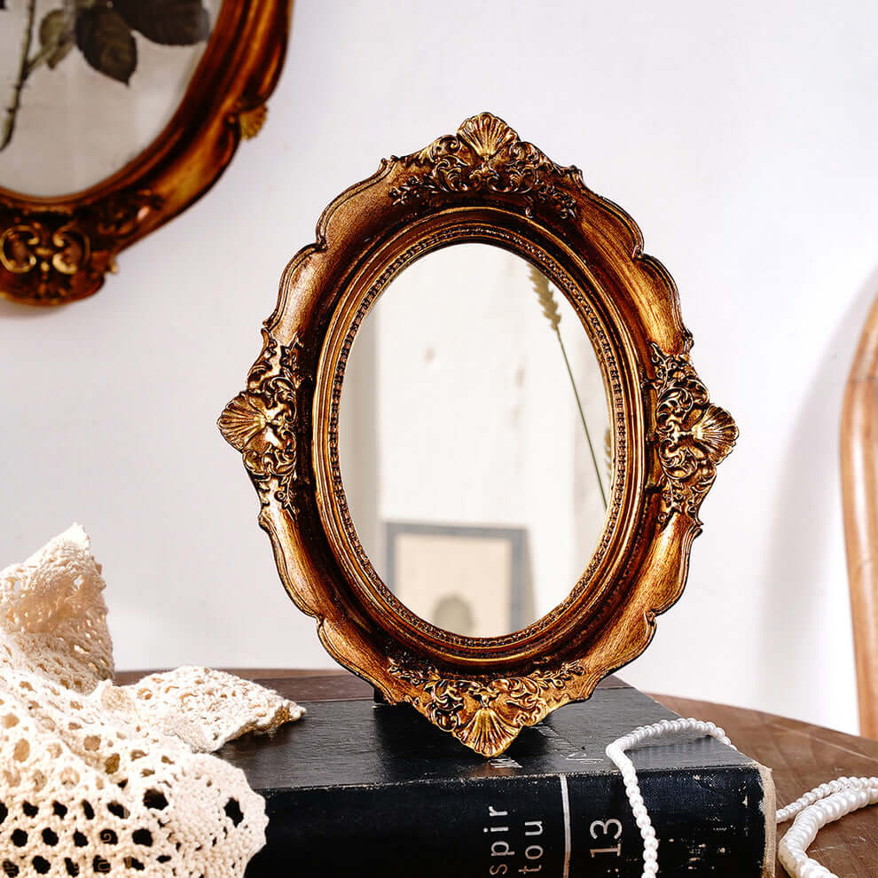 Decorative gold-framed mirror on a book with a white background