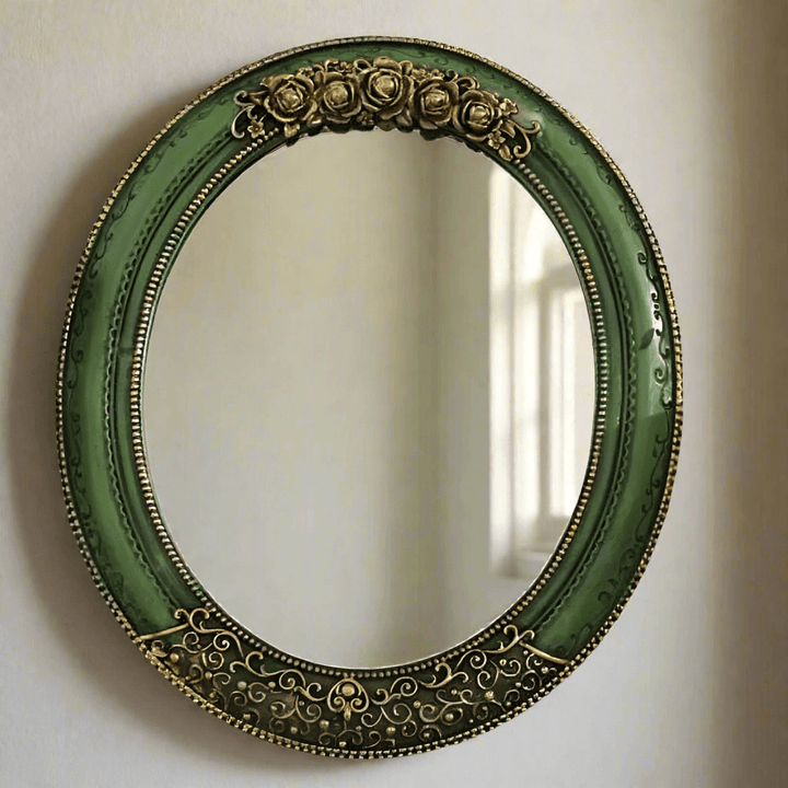 Antique green oval wall mirror with ornate gold detailing, adding vintage elegance to home décor.