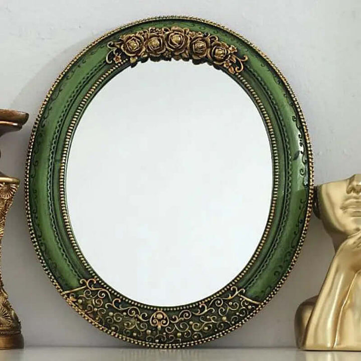 Antique green oval wall mirror with ornate gold detailing and floral accents, vintage elegance for home decor.