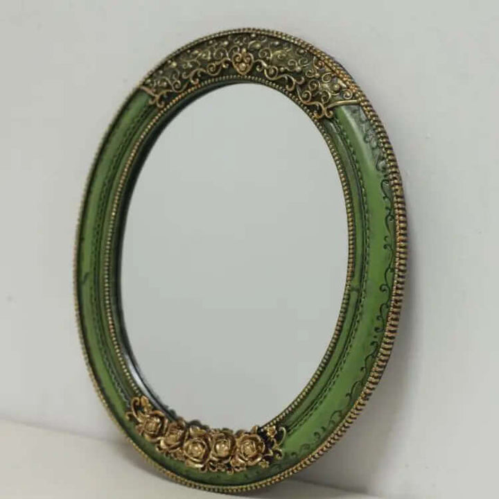 Antique green oval wall mirror with ornate gold detailing, perfect for vintage home décor.