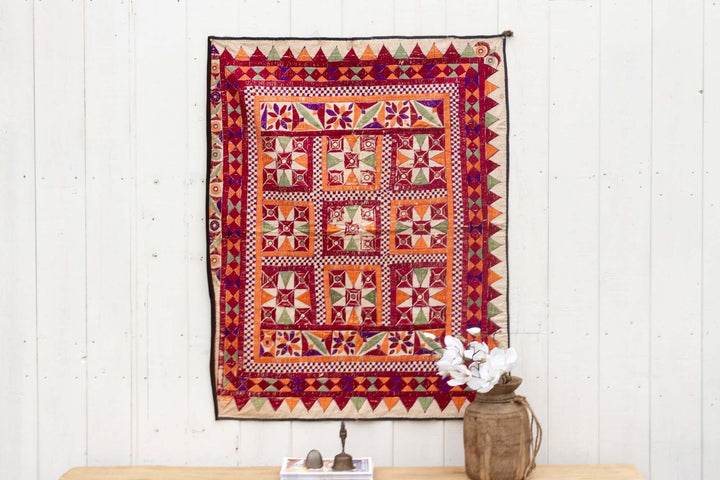 Colorful tapestry with geometric patterns on a white wooden wall