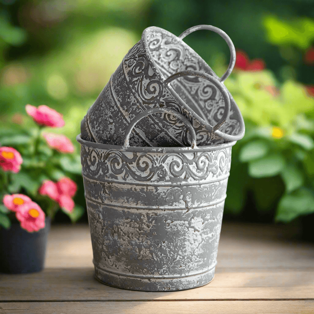 Set of 2 antique metal buckets with handles, featuring ornate filigree and a distressed finish, ideal for rustic décor.