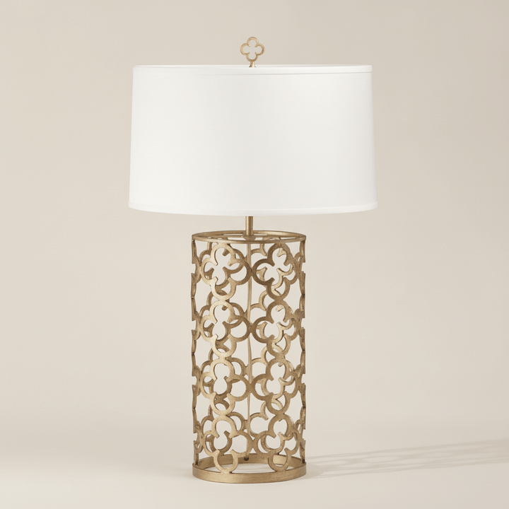 Decorative table lamp with intricate metal base and white shade on a beige background