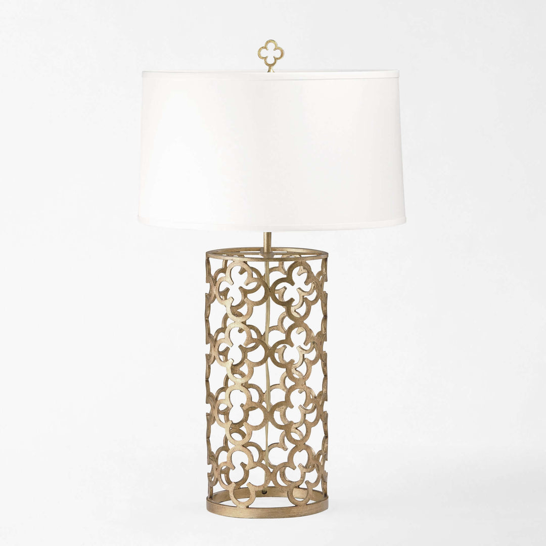 Decorative table lamp with intricate metal base and white shade on a light gray background