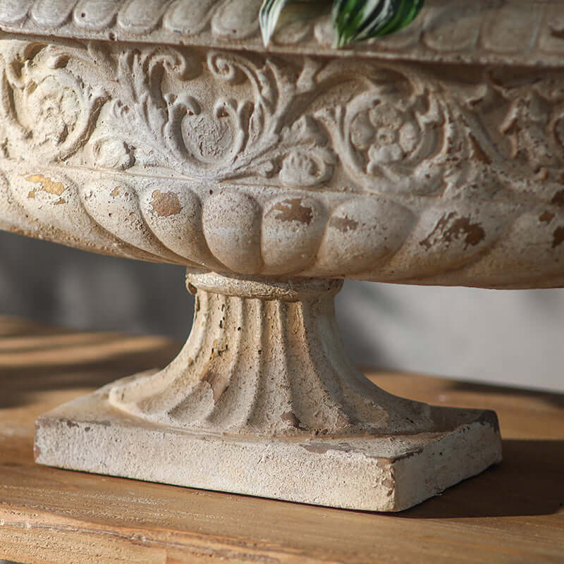 Decorative stone urn with intricate patterns on a wooden surface