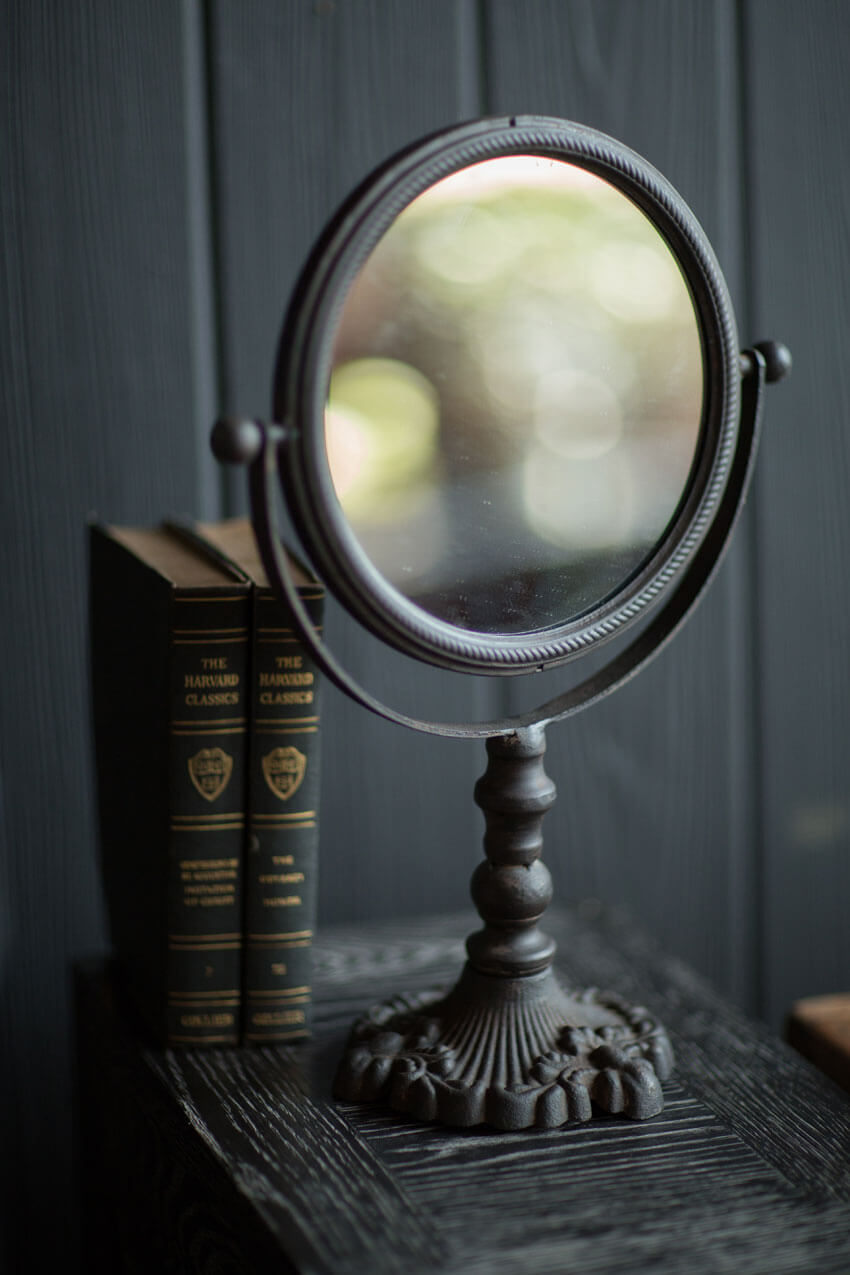 Antique swivel tabletop makeup mirror in ornate cast iron frame, perfect for vintage home decor.