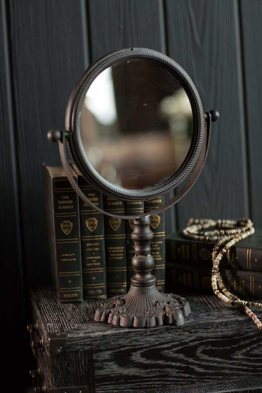 Antique swivel tabletop makeup mirror with ornate cast iron frame, perfect for vintage home décor.