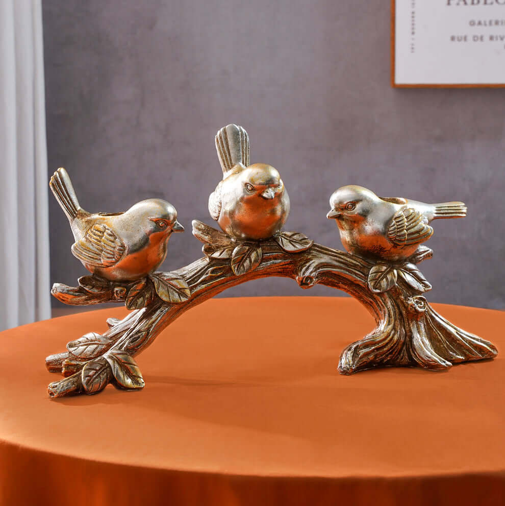 Decorative sculpture of three birds on a branch with a neutral background