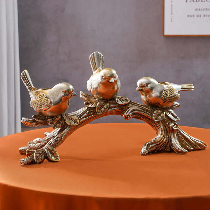 Decorative sculpture of three birds on a branch with a neutral background