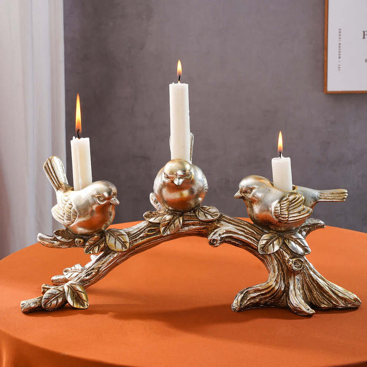Decorative candle holder with bird designs on an orange surface.