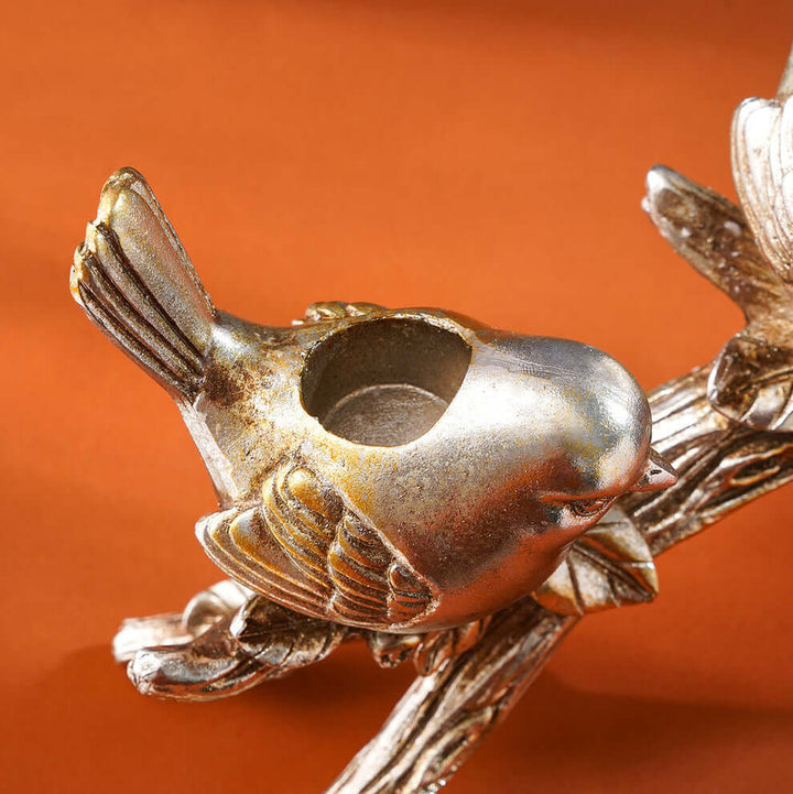 Bronze bird-shaped candle holder on an orange background