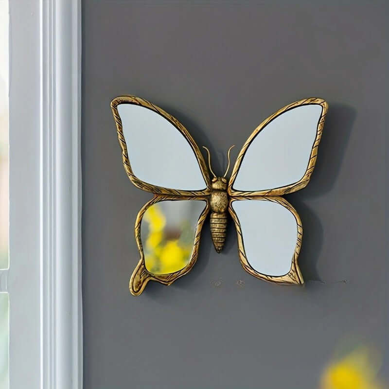 Decorative butterfly mirror with gold frame on a gray wall