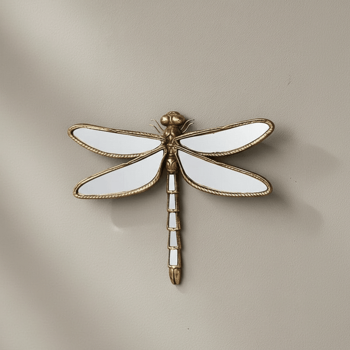 Decorative wall mirror of a dragonfly with gold and white details on a beige background