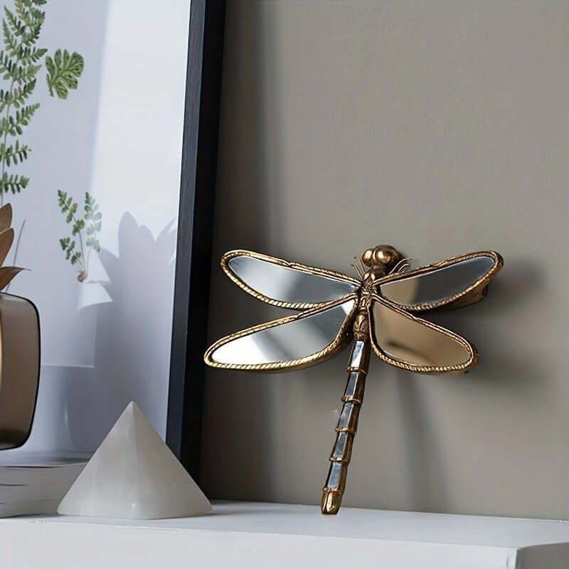 Decorative gold dragonfly on a shelf with a neutral background