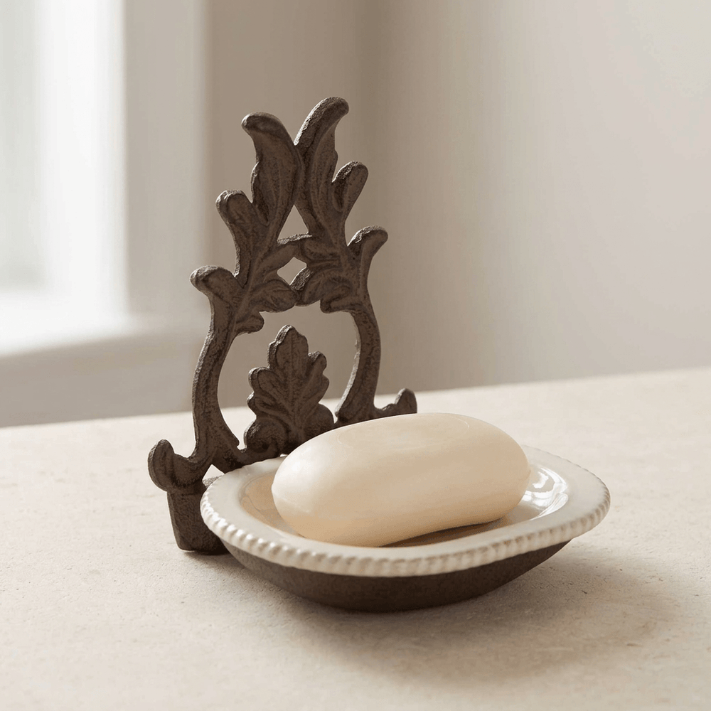 Bellavita cream ceramic soap dish holding an ivory oval soap bar, with ornate dark acanthus metal backing