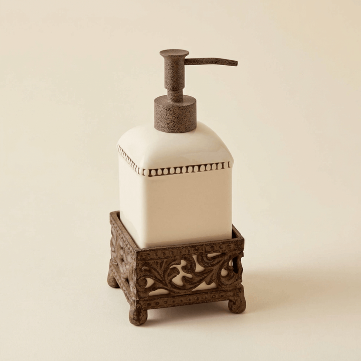 Cream Bellavita pump dispenser in an ornate brown metal holder on an ivory studio background