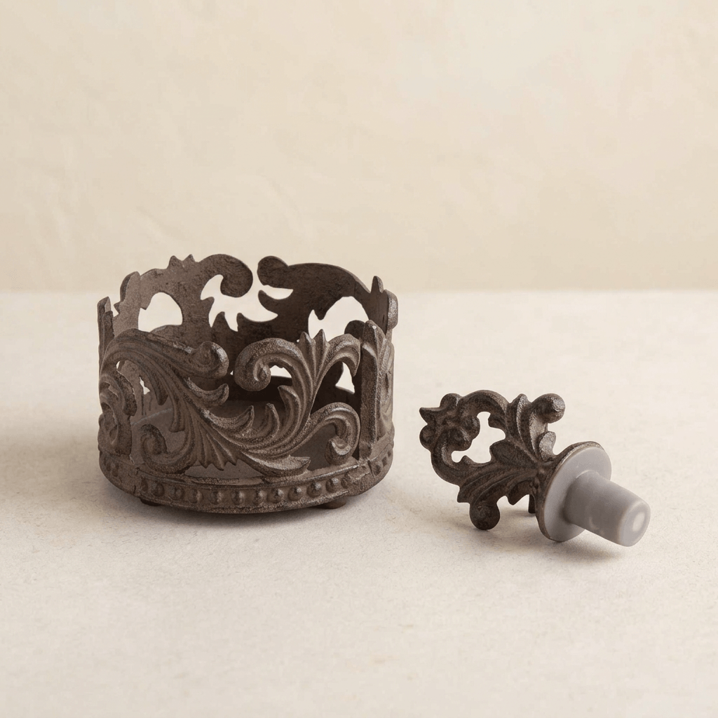 Ornate dark brown acanthus wine bottle holder and matching stopper displayed on a pale tabletop